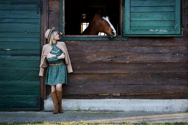 Mooi meisje in boho-stijl praat door een raam met een paard