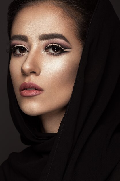 Mooi meisje in de Arabische sjaal met oosterse make-up