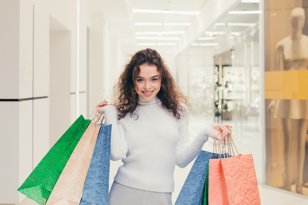 Mooi meisje in de winkel met gekleurde tassen