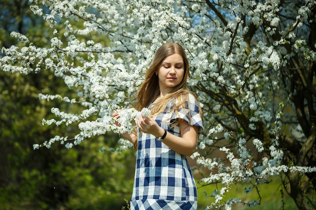 Mooi meisje in een jurk die in het lentebos loopt waar de bomen bloeien