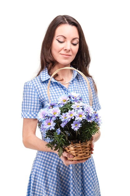 Mooi meisje in een jurk in een blauwe kooi met bloemen chrysanten in handen op een witte achtergrond