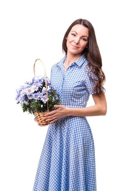 Mooi meisje in een jurk in een blauwe kooi met bloemen chrysanten in handen op een witte achtergrond