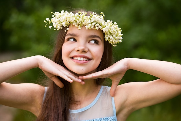 Mooi meisje in een krans van lelietje-van-dalen en met een boeket. vrouw verzamelt lelietje-van-dalen in de tuin.