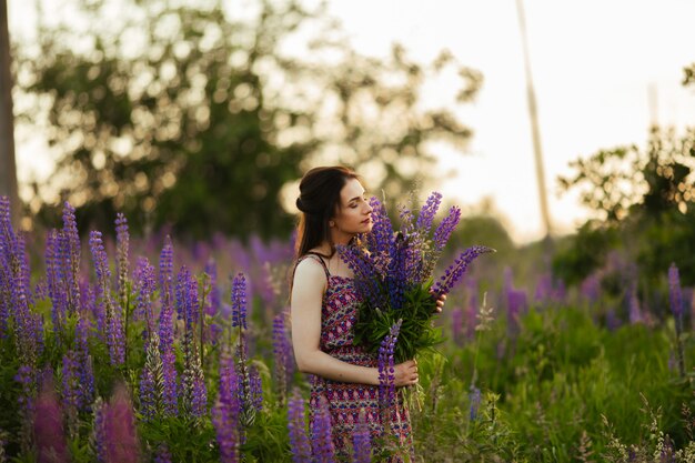 Mooi meisje in een lupine veld. Meisje met een boeket van lupines