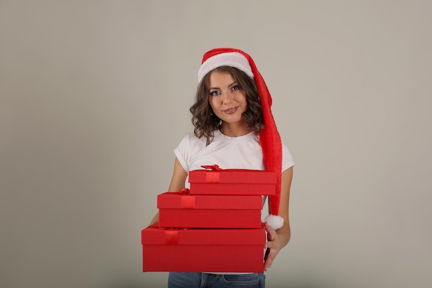 mooi meisje in een wit T-shirt met een kerstmanhoed houdt rode geschenkdozen in haar handen