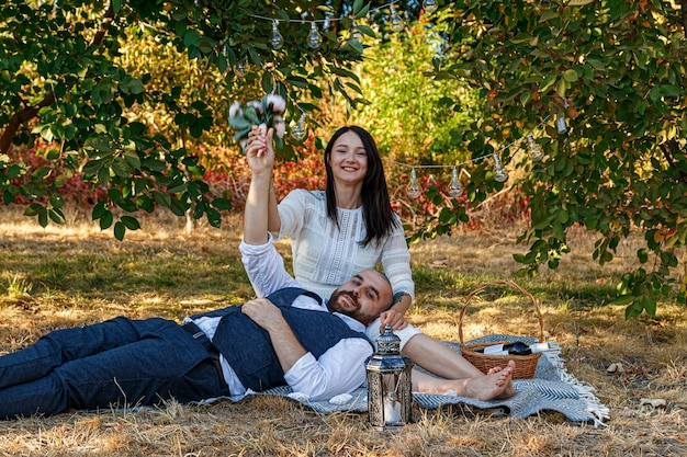 Mooi meisje in een witte jurk en een man liggen op een open plek voor een picknick