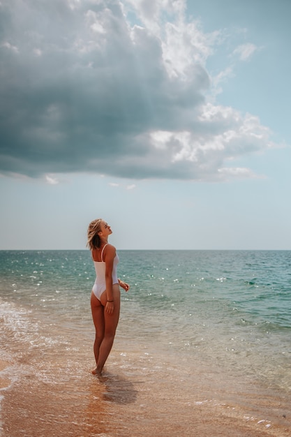 Mooi meisje in een witte Romper loopt langs de kust van de azuurblauwe zee