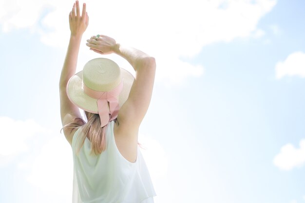 Mooi meisje in een zomerhoed tegen de lucht