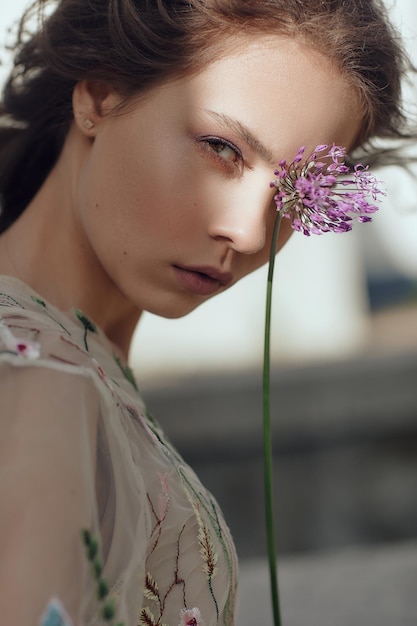 Mooi meisje in een zomerjurk poseren tegen een achtergrond van bloemen