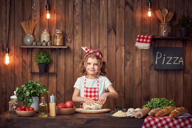 Mooi meisje in geruit schort het kneden brooddeeg voor pizza