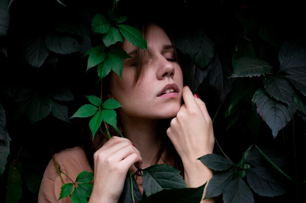 Mooi meisje in groene bladeren portret van een aantrekkelijke vrouw in planten schattig gezicht op een achtergrond