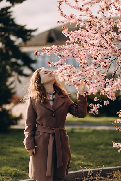 Mooi meisje in het voorjaarspark met amandel bloemen levensstijl portret gelukkige vrouw met bloeiende kersenboom
