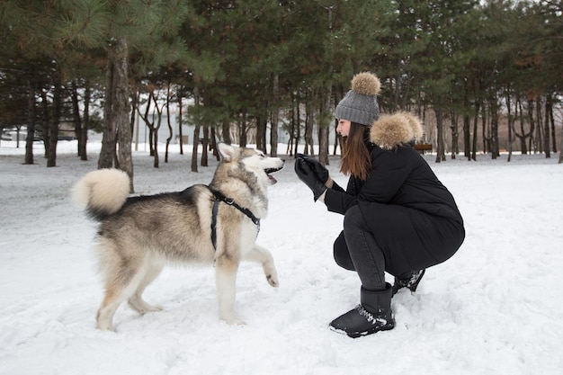 Mooi meisje in het winterbos met hond Spelen met de hond Siberische husky