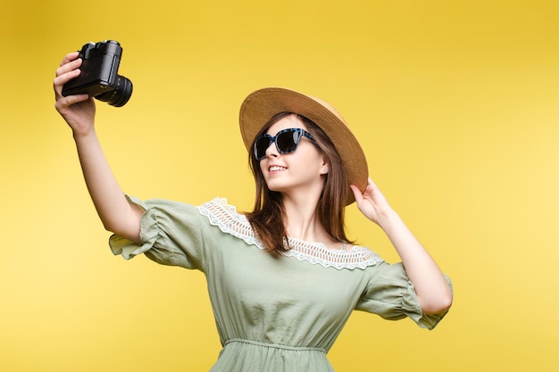 Mooi meisje in hoed en zomerjurk die selfie op camera neemt