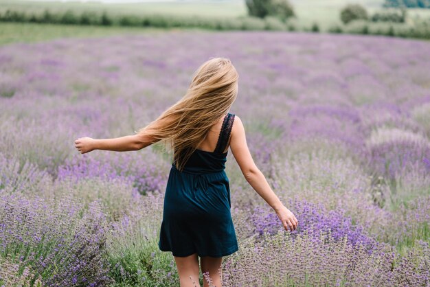Mooi meisje in jurk rennen en vliegen met lang haar op paarse lavendelveld mooie vrouw lopen op het lavendelveld bij zonsondergang geniet van de bloemen glade zomer natuur