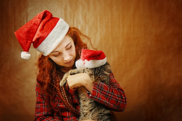 Mooi meisje in kerstmuts met kat in kerstman hoed roodharige vrouw met dreadlocks in plaid...