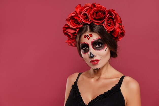 Mooi meisje in la muerta kleding en schedel make-up op zoek naar camera tijdens halloween