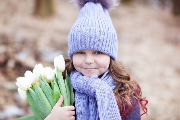 Mooi meisje in park met een boeket van witte tulpen. Boeket tulpen. Bloemen als cadeau voor moederdag voor vrouwen. 8 maart. Het concept van de lente en vrouwendag. Pasen. Close-up portret kind