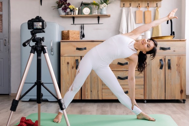 Mooi meisje in sportkleding doet yoga en schiet video op voor haar blog