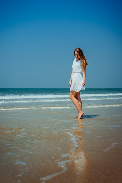 Mooi meisje in witte jurk Geniet en ontspannen op het strand