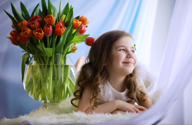 Mooi meisje in witte jurken met een prachtig boeket van de eerste tulpen. Internationale Vrouwendag. Meisje met tulpen.