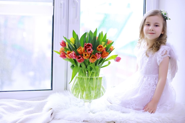 Mooi meisje in witte jurken met een prachtig boeket van de eerste tulpen Internationale Vrouwendag Meisje met tulpen