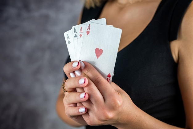 Mooi meisje in zwarte jurk houdt aas van pokerkaarten in de buurt van sexy decolleté vrouw in poker