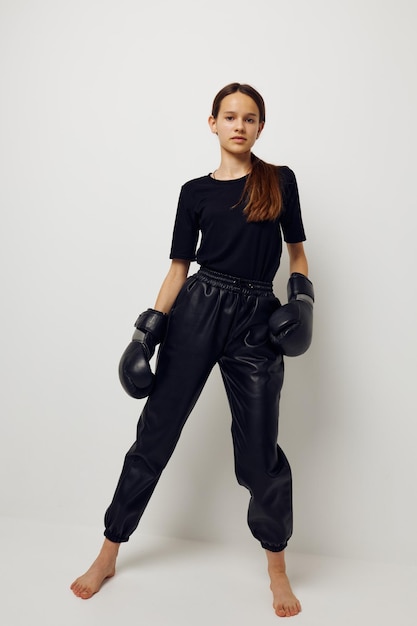 Mooi meisje in zwarte sport uniform bokshandschoenen poseren geïsoleerde achtergrond