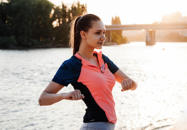 Mooi meisje kneden voor het joggen op de oever van de rivier