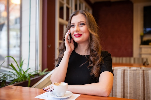 Mooi meisje koffie drinken en praten aan de telefoon