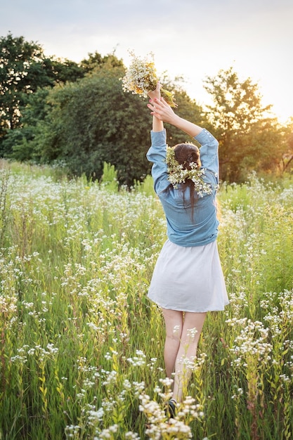 Mooi meisje lopen op veld in de zomer met wilde bloemen