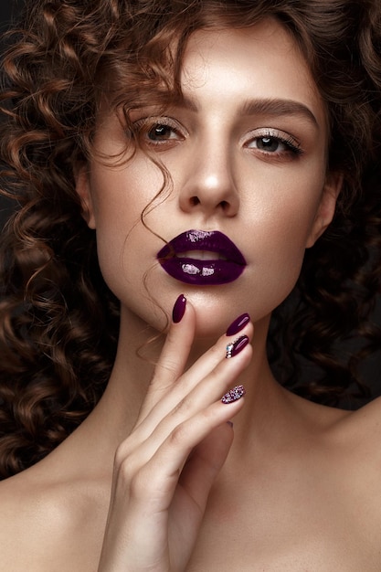 Mooi meisje met avond make-up paarse lippen krullen en ontwerp manicure nagels schoonheid gezicht