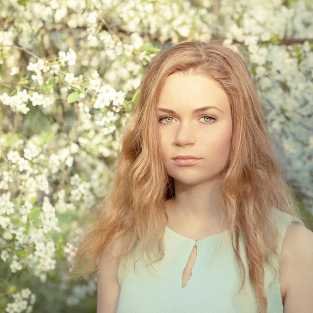 Mooi meisje met blond lang haar in de bloeiende lentetuin