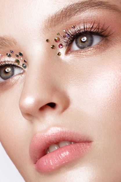 Mooi meisje met creatieve lichte make-up met strass steentjes. Mooi gezicht.