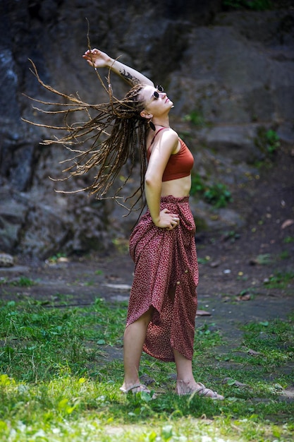 Mooi meisje met dreadlocks gekleed in hippiestijl poseert buitenshuis