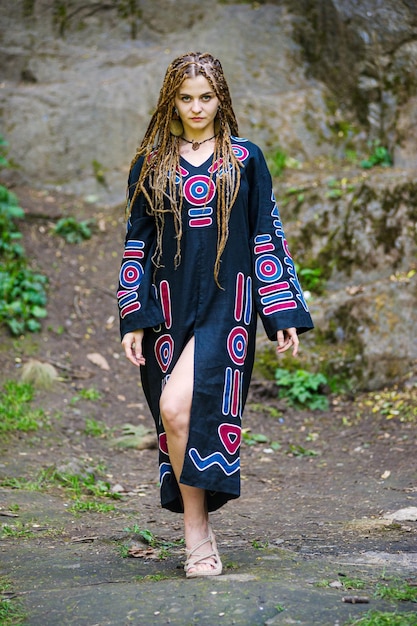 Mooi meisje met dreadlocks gekleed in hippiestijl poseert buitenshuis