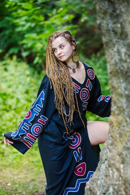 Mooi meisje met dreadlocks gekleed in hippiestijl poseert buitenshuis