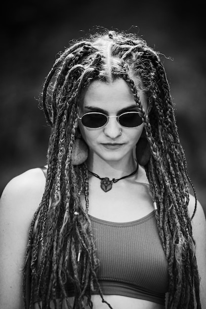 Mooi meisje met dreadlocks gekleed in hippiestijl poseert buitenshuis