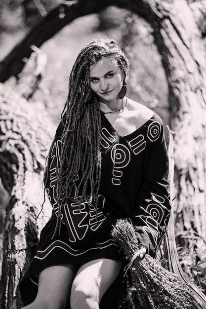 Mooi meisje met dreadlocks gekleed in hippiestijl poseert buitenshuis