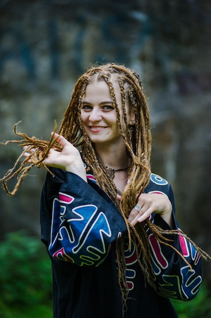Foto mooi meisje met dreadlocks gekleed in hippiestijl poseert buitenshuis