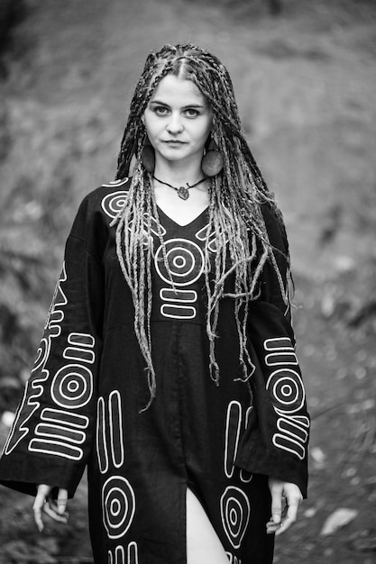 Foto mooi meisje met dreadlocks gekleed in hippiestijl poseert buitenshuis