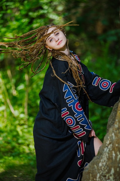 Mooi meisje met dreadlocks gekleed in hippiestijl poseert buitenshuis