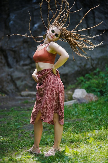 Mooi meisje met dreadlocks gekleed in hippiestijl poseert buitenshuis