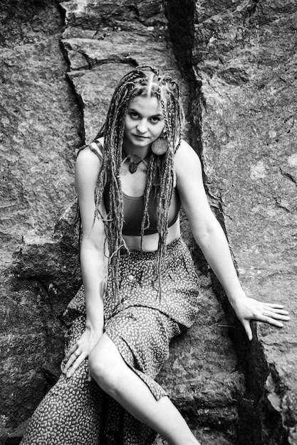 Mooi meisje met dreadlocks gekleed in hippiestijl poseert buitenshuis