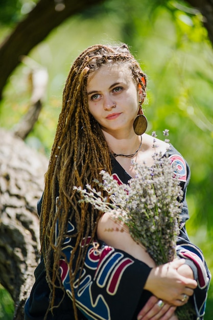 Mooi meisje met dreadlocks gekleed in hippiestijl poseert buitenshuis