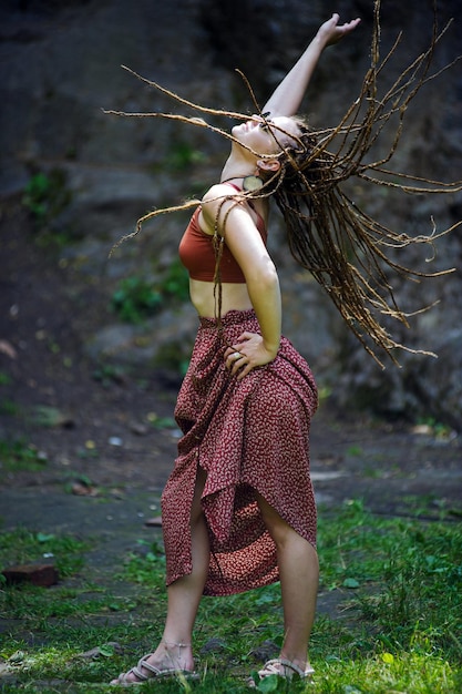 Mooi meisje met dreadlocks gekleed in hippiestijl poseert buitenshuis