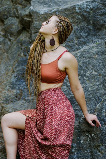 Mooi meisje met dreadlocks gekleed in hippiestijl poseert buitenshuis