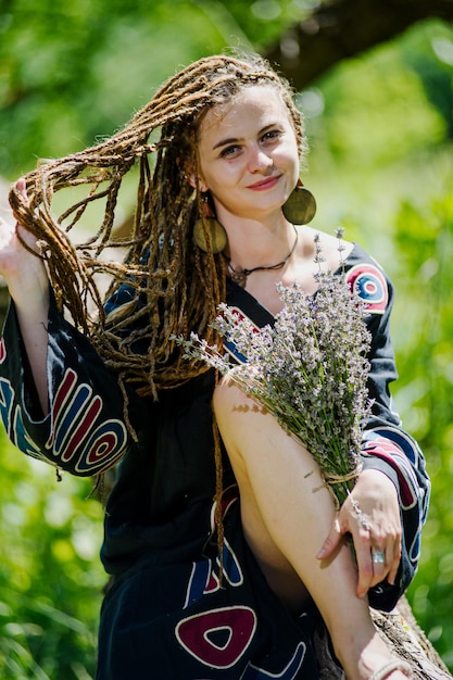 Mooi meisje met dreadlocks gekleed in hippiestijl poseert buitenshuis