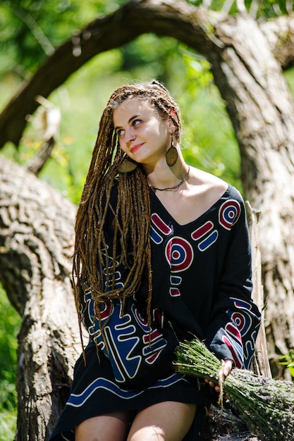 Mooi meisje met dreadlocks gekleed in hippiestijl poseert buitenshuis