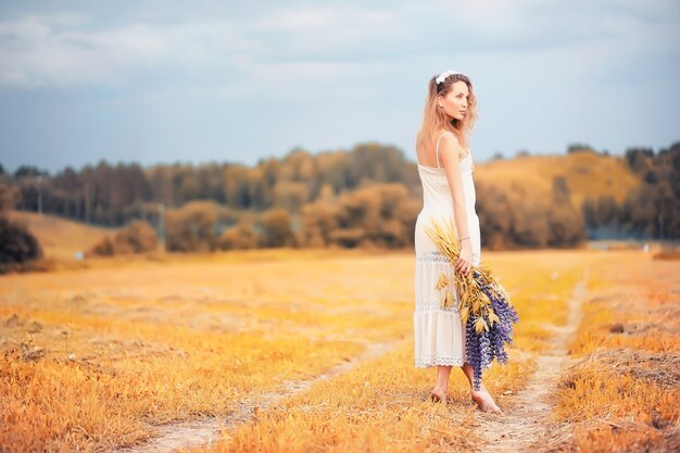 Mooi meisje met een boeket blauwe bloemen op de natuur in de herfst